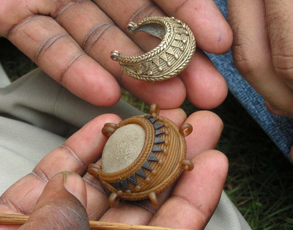 Hands holding ornate crescent and round jewelry pieces