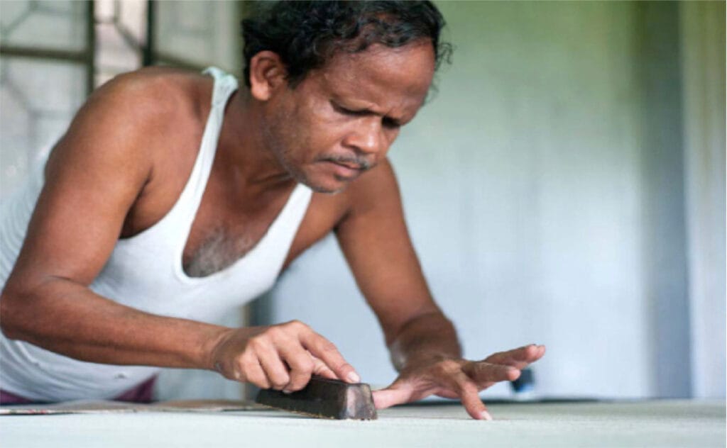Man sanding a wooden surface indoors