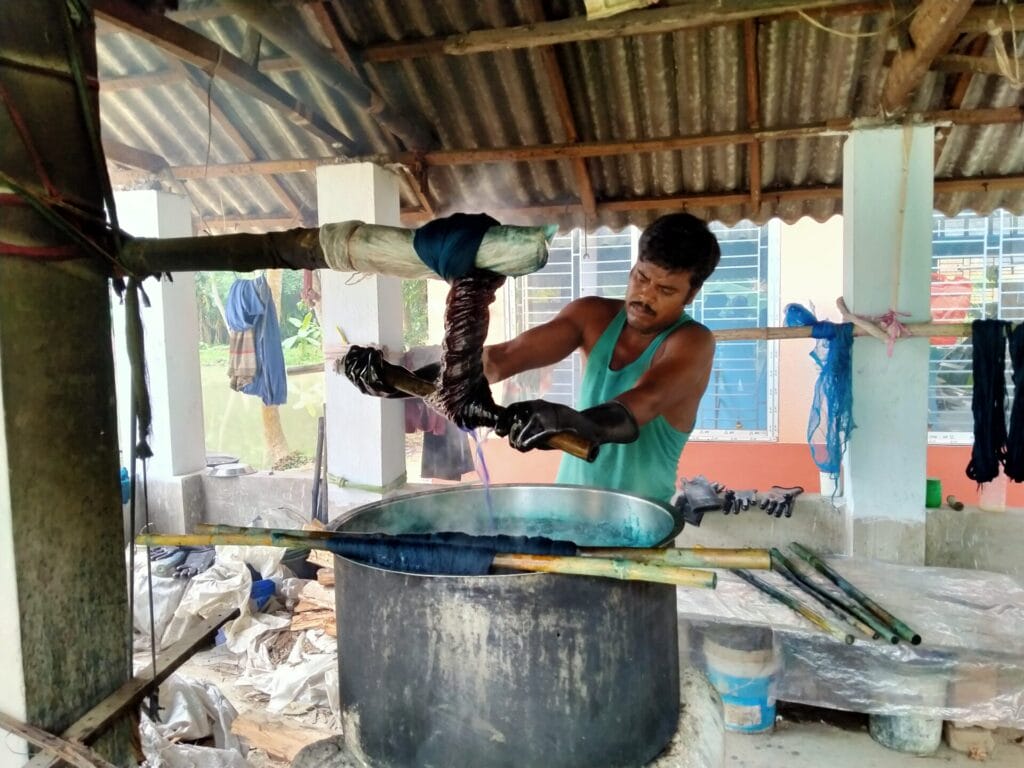 Man dyeing fabric in steaming vat workshop