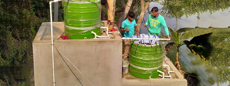 2 Indian men working on installation of tanks for a waste water treatment system