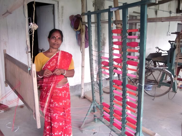 Woman weaving thread with pink spools indoors