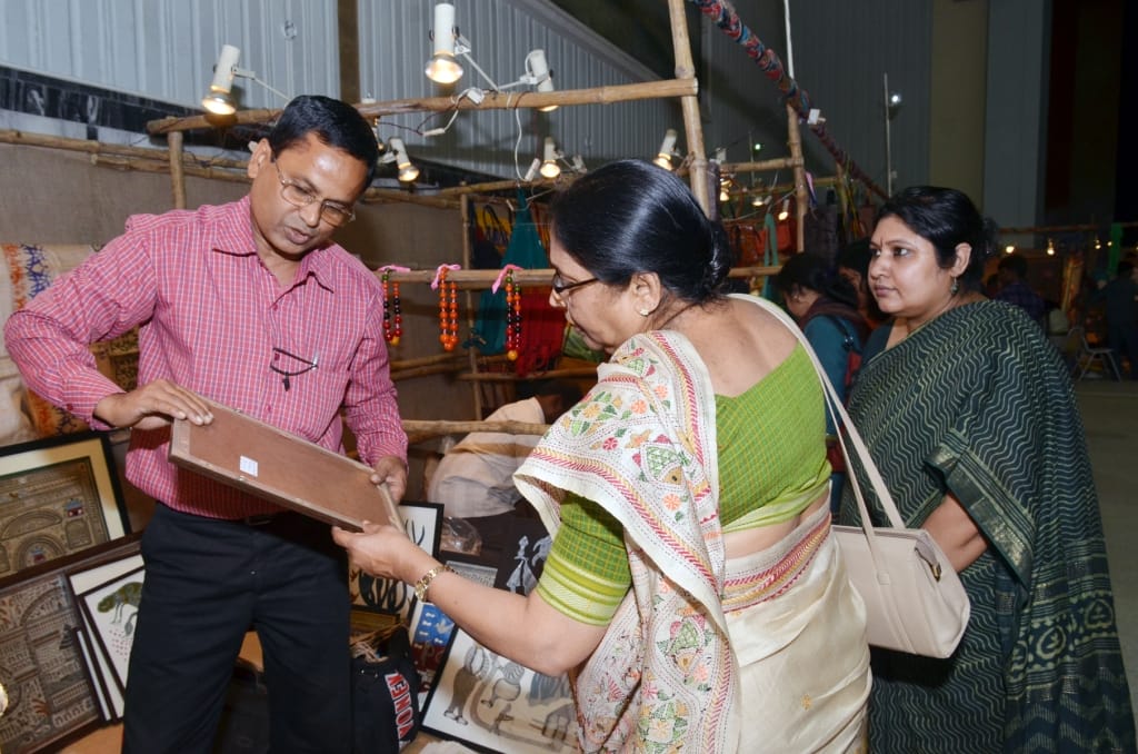 Man showing framed artwork to women at market