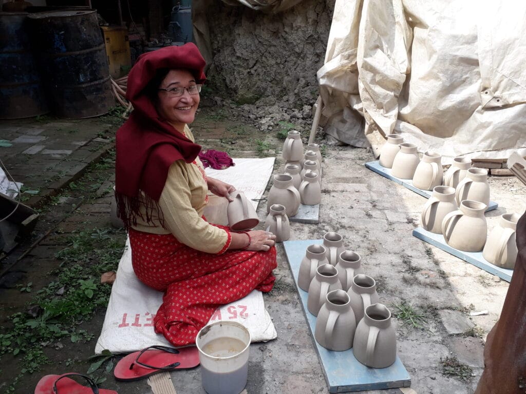 Woman shaping clay jugs outdoors